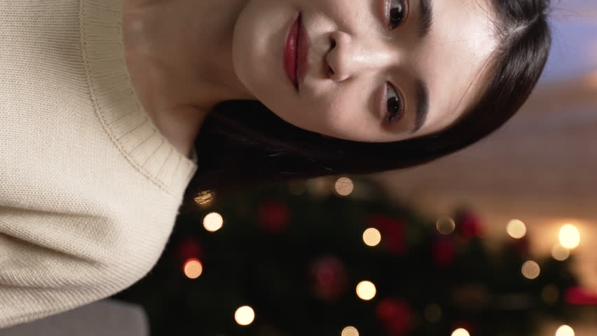 Vertical Screen: man giving Christmas gift to pretty girlfriend and hugging by xmas tree with lights and red ribbons in the cozy living room at home in night. | Shutterstock HD Video #1111932589