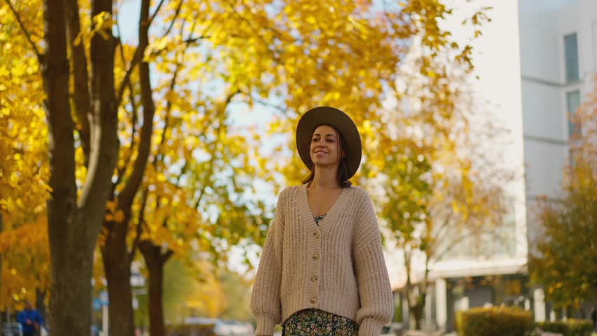 Autumn portrait of bright beautiful smiling woman wearing in dress, knitted sweater and hat. girl on yellow leaves background looking at camera | Shutterstock HD Video #1111932765
