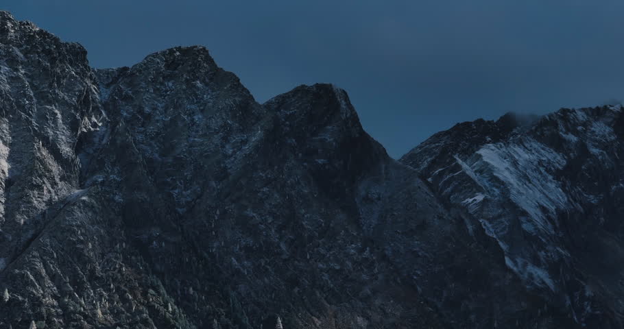 Beautiful right to left aerial slow speed 7x zoomed 4k mountain view of Austrian Alps. High quality prores footage in daylight with shadows from clouds, rocky steep hill with contrasting snow