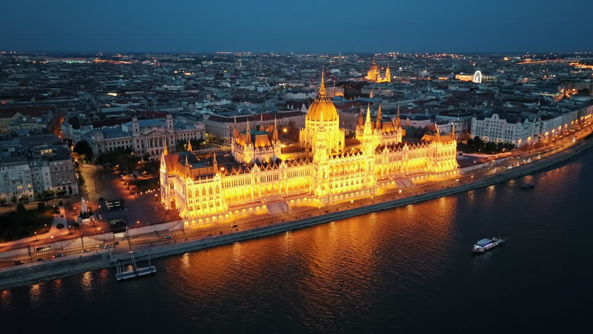 Aerial view national building symbol residence of Hungarian Parliament, Budapest night city lights against backdrop sunset evening on sunny day in summer view from other bank of Danube River. Travel