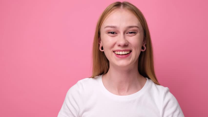 A cute girl stands on a pink background and points to a place for text.  | Shutterstock HD Video #1111934091