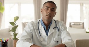 Biracial male doctor making video call in bright room, slow motion. Medical services, telemedicine and healthcare, unaltered.