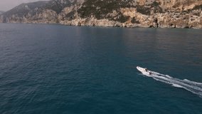 Aerial drone video of tropical paradise turquoise beach in Mediterranean Island of La Maddalena Archipelago, Costa Smeralda, Sardinia. boat tracking