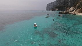 Aerial drone video of tropical paradise turquoise beach in Mediterranean Island of La Maddalena Archipelago, Costa Smeralda, Sardinia. Boat on water 