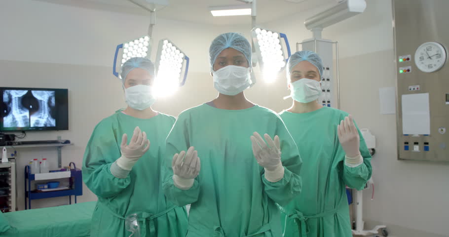 Portrait of diverse female surgeons wearing surgical gowns in operating theatre, slow motion. Hospital, surgery, teamwork, medicine, healthcare and work, unaltered. Royalty-Free Stock Footage #1111939951