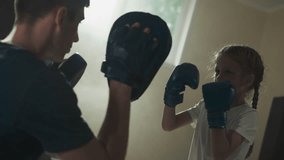 Child punches and blocks with instructor in gym. Young trainer with little girl do fighting exercise in boxing club slow motion. Martial arts school - Powered by Shutterstock - Get 15% off with code: PIKWIZARD15