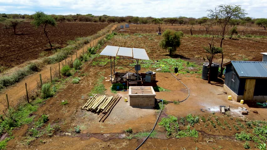 Aerial drone view into large solar panels at a solar farm at bright sunset. Solar cell power plants.Aerial drone view in Africa water system pumped with Solar panels. smart agriculture.