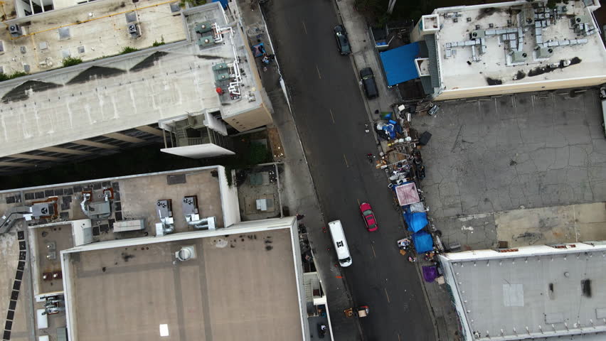 Aerial view of traffic in middle of unhoused people on the streets of Skid Row, LA