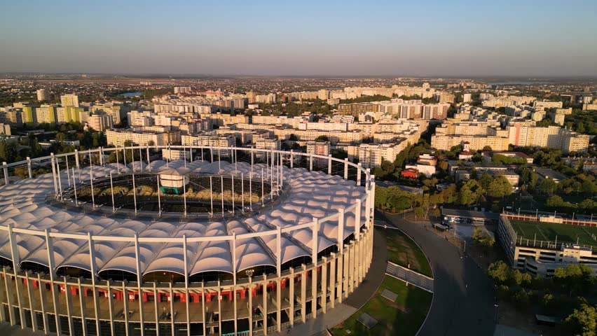 4k aerial view of a spectacular city roundabout with lush green vegetation. Summer sunset shot of an intersection in Bucharest - Romania. Drone high angle footage. Top down parked cars in city.
