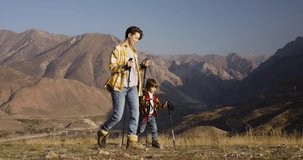 Mother and son conquer mountain, trekking poles backpacks. Step by step together mother and her son traverse rocky path. Reaching new heights, experience invigorating embrace of autumn sunlight
