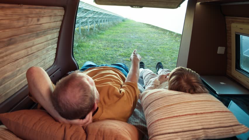 Grandfather points out solar panels to his grandchild, sharing knowledge while lying in a camper. | Shutterstock HD Video #1111949701