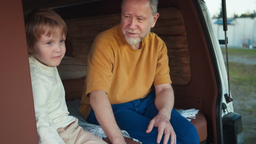 Excited boy shares a smile with grandpa at solar plant, both enjoying their time together in the camper van | Shutterstock HD Video #1111949705