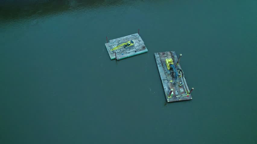 Excavators on floating dock pontoon on mississippi river near Centennial Bridge in Davenport, Iowa, USA