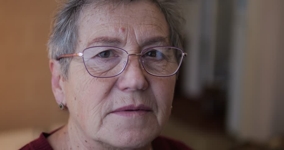 The face of an old woman in glasses. A woman with age-related wrinkles on her face smiles easily. | Shutterstock HD Video #1111951041