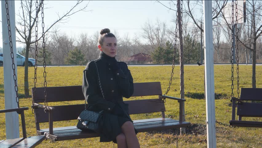 Lonely stylish woman sits on park bench, she is bored alone and looks around. | Shutterstock HD Video #1111951079
