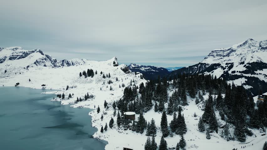 Snowy Engelberg with rocky mountain peaks and Truebsee Lake. Majestic winter natural landscape of Swiss Alps with summits covered with fresh snow. Rocky snowy mountain ranges and peaks