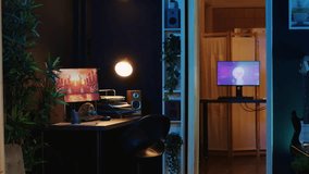 Work desk with computer and house plants in empty house interior with warm lighting. Living room illuminated by neon lights with 3D rendered animations running on powerful PC monitors