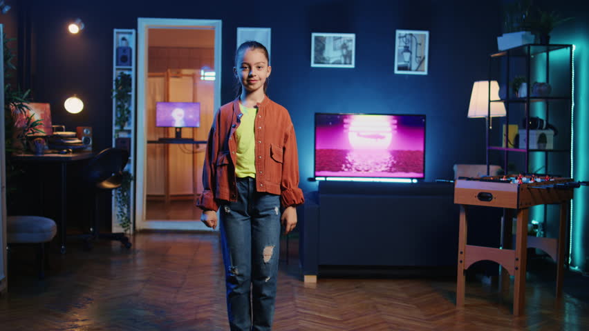 Close up shot of cheerful child mesmerizing her followers with incredible dance moves in neon lit home studio. Internet star at home showcasing cool dancing skills, filming family friendly content