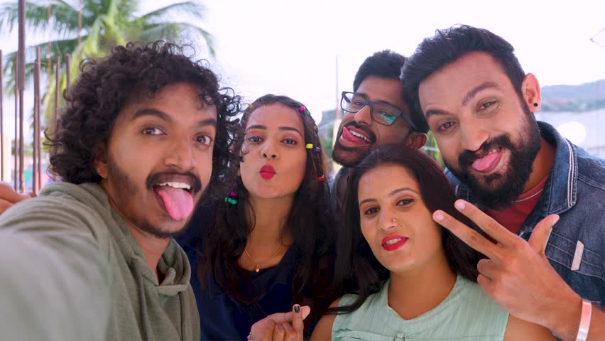 Group of young Indian friends taking selfie with grimacing faces by looking camera during reunion party - concept of friendship bonding, zen z lifestyle and social media sharing Royalty-Free Stock Footage #1111963821