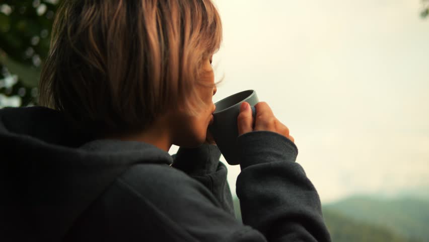 Young Woman Sips Fresh Hot Coffee on Forest Cabin Terrace with Mountain and Clouds View, High Quality Cozy Zen Morning Bliss Moment Concept Footage. Chiang Mai, Northern Thailand. | Shutterstock HD Video #1111965739