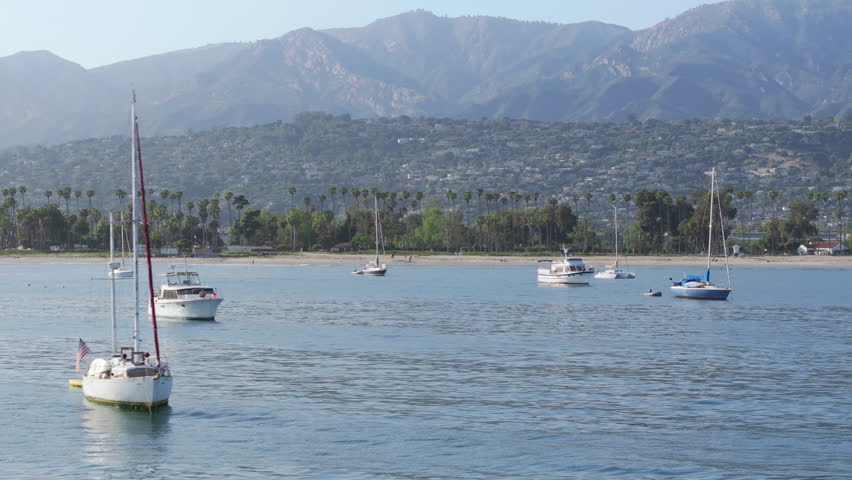 Scenic view of yachts floating in Santa Barbara Harbor, California, USA. Shot from Point Castillo on Santa Barbara city surrounded mountains and Pacific Ocean. Sailboats docked in city marina  | Shutterstock HD Video #1111965771