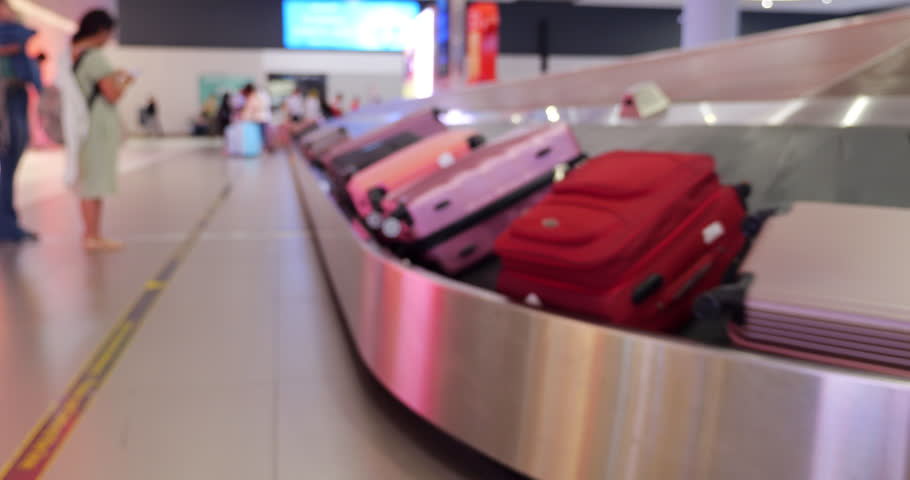 Blurred view, colorful suitcases move at baggage carousel in modern airport, creating abstract scene. Variety of colors, including pink, adds dynamic touch. Only few passengers wait for their luggage | Shutterstock HD Video #1111974829