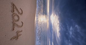 New year 2024 text on the sea sand and beautiful beach sunrise vertical video