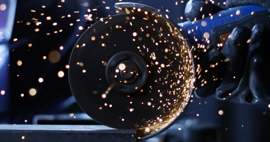 Super slow motion close up of blacksmith welder is smoothing metal steel with industrial angle grinder with flying sparks in workshop at 1000 fps.
