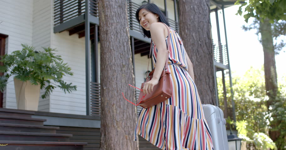 Happy asian woman with suitcase walking on stairs of home on sunny day, slow motion. Summer, returning home, travel, unaltered. | Shutterstock HD Video #1111978543