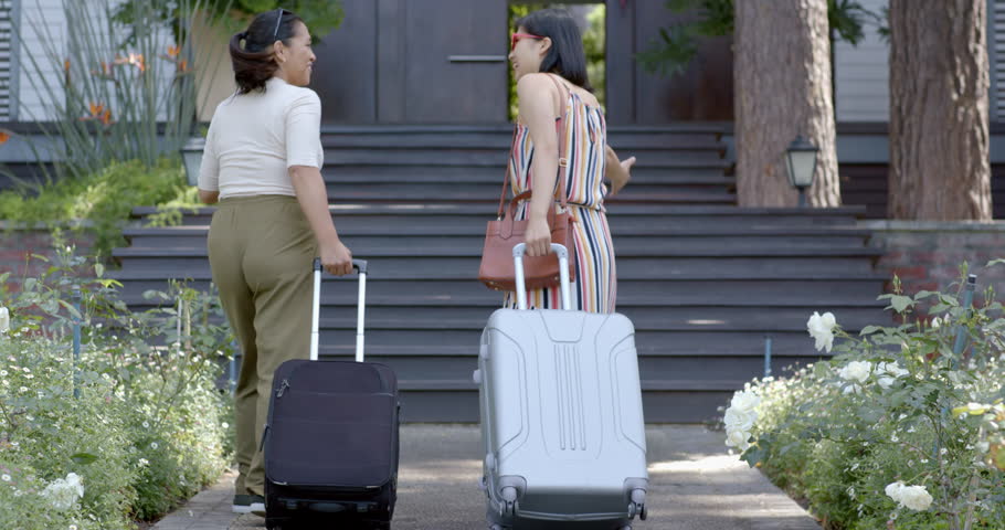 Happy asian female friends with suitcases walking on stairs of home on sunny day, slow motion. Summer, returning home, travel, friendship, unaltered. | Shutterstock HD Video #1111978597