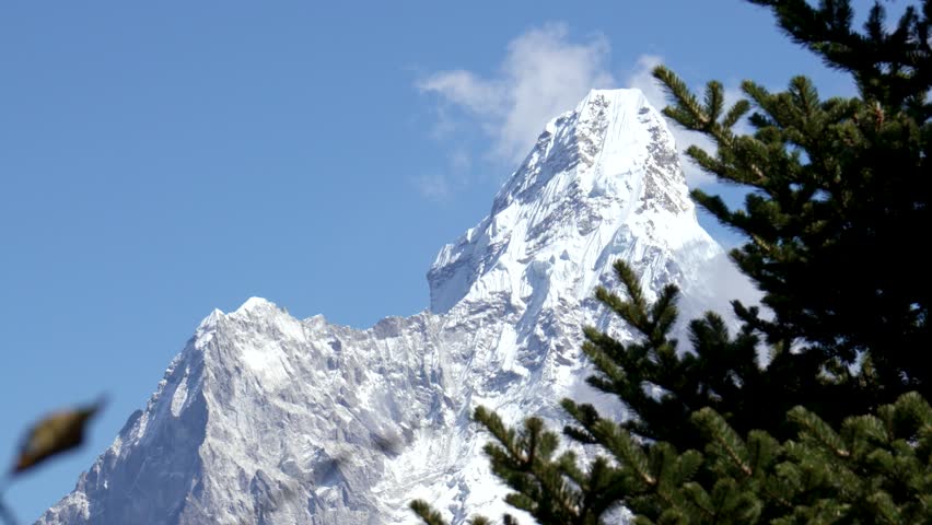 Snow covered peak Ama Dablam rise above barren landscape of Himalayan Mountains. Trekking in Nepal to see highest mountains in world. Against coniferous trees Royalty-Free Stock Footage #1111979339