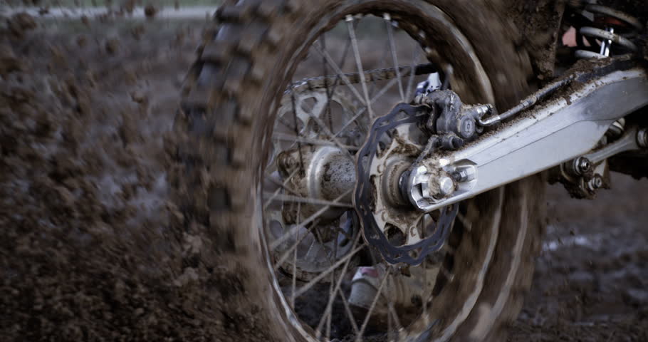 Slow motion macro of dirt splashing from motorbike rear wheel while rider is in action in motocross race.