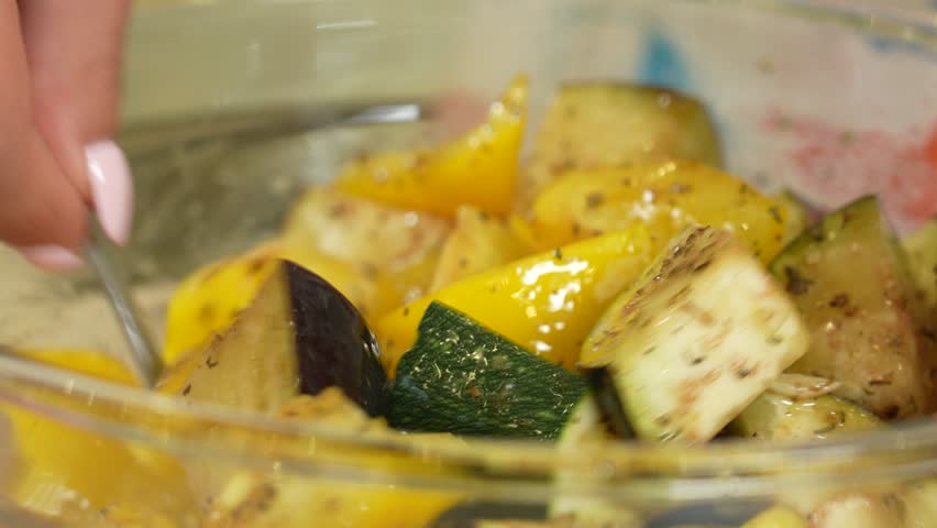 Seasoning fresh vegetables in a glass bowl for baking
