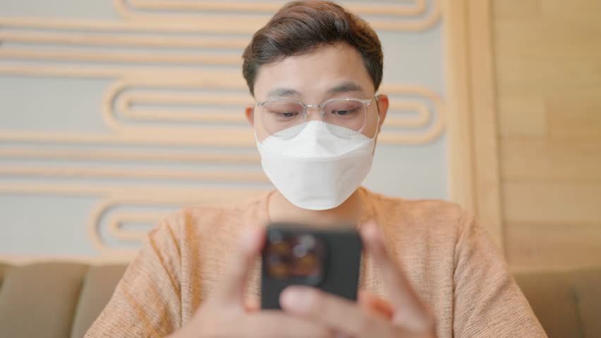 Asians wearing masks chatting on smartphones to protect against coronavirus | Shutterstock HD Video #1111986113