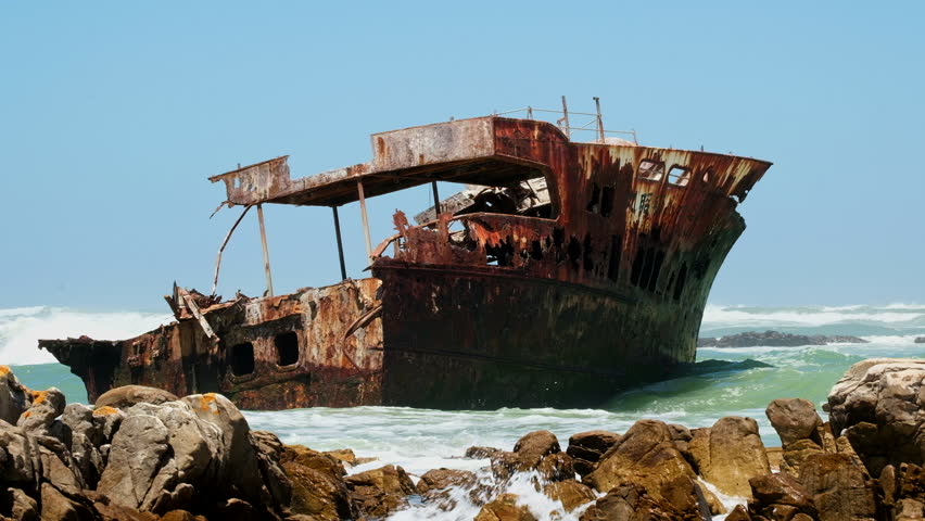 Waves crash into old rusted weather-beaten shipwreck on Cape Agulhas coastline Royalty-Free Stock Footage #1111988377
