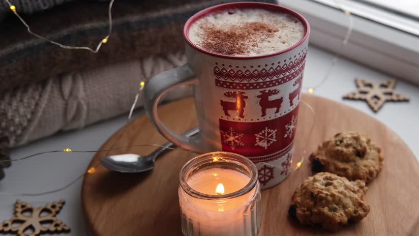 Winter windowsill still life. Red ceramic cup of hot coffee on window sill. Christmas decorations on the background. Cozy home picture. Warm woolen knitted sweaters, Burn Candle, Cookies. Stock photo | Shutterstock HD Video #1111989701