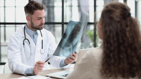 Young physiotherapist watching x-ray while sitting at the table at the reception - Powered by Shutterstock - Get 15% off with code: PIKWIZARD15
