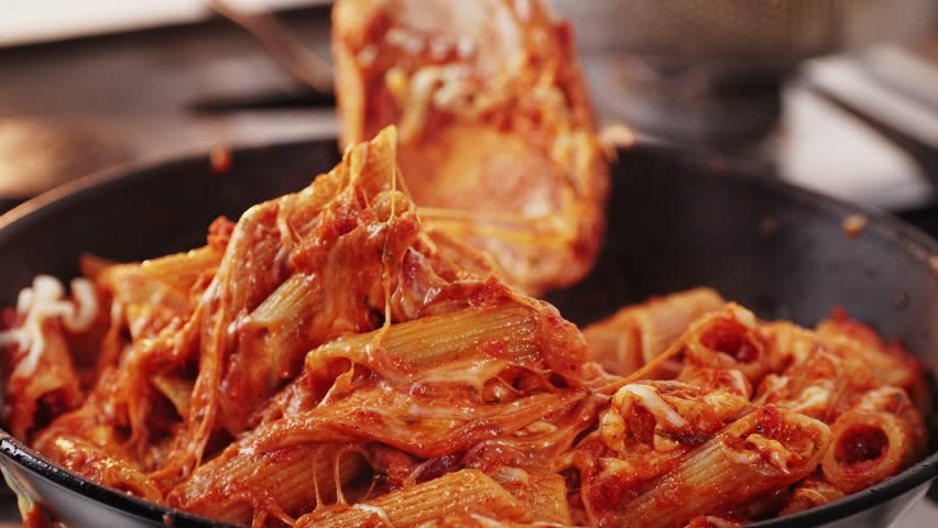 Chef cooking penne pasta with tomato sauce and mozalerra cheese in pan, close up. Cooking traditional italian cuisine, food in Italy.