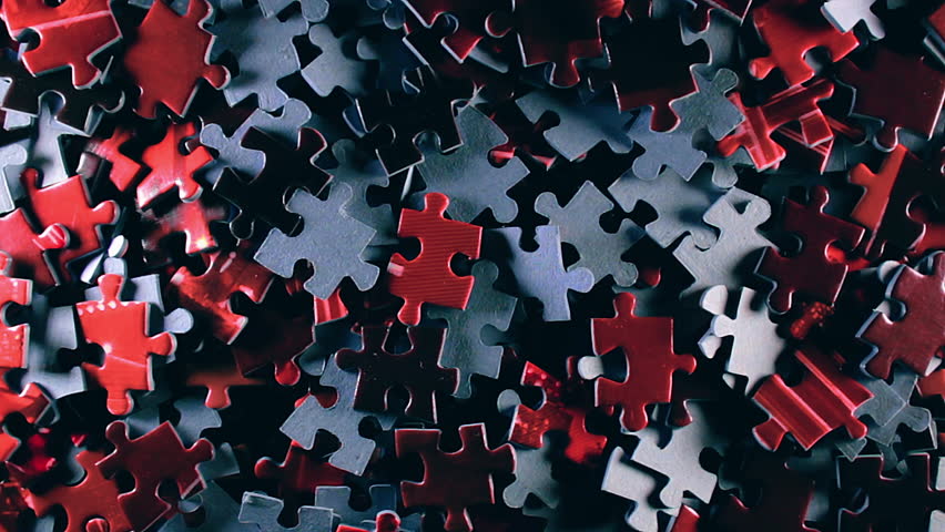 Background of Colored Puzzle Pieces that Slowly Rotating Counterclockwise - Top View. Texture of Incomplete Red and Grey Jigsaw Puzzle with Low Key Light - Left Rotation | Shutterstock HD Video #1111996447