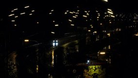 Cars drive along the night road in the rain. Cars headlights and night city lights are reflected on the wet road. Beautiful view of cars and vehicles driving on the highway. 4k Video footage for news