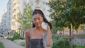 Stylish african american woman walking green street portrait. Trendy confident model looking camera touching braids closeup. Smiling black hair lady strolling alley alone. Fashionable girl lifestyle  - Powered by Shutterstock - Get 15% off with code: PIKWIZARD15