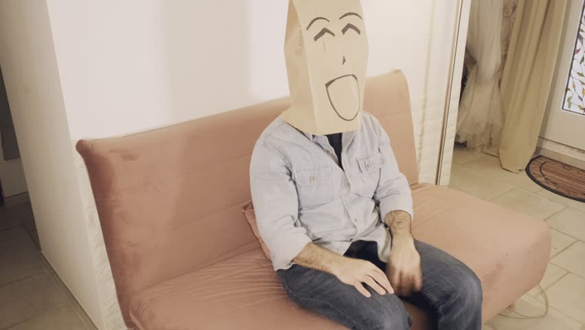 A man wearing a breadbag face, sitting on the sofa at home, happily smiling, opening his arms with a contented mood.
 | Shutterstock HD Video #1112003987