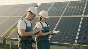 Two technicians lady and guy they walking through the solar panels rows. - Powered by Shutterstock - Get 15% off with code: PIKWIZARD15