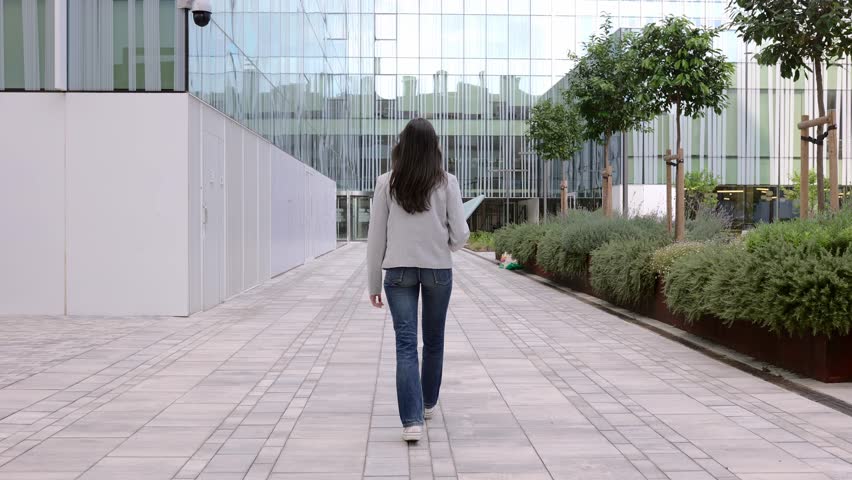 Rear view of young adult business woman walking in a co-working office area. Professional confident empowered female entrepreneur going to work at the office. | Shutterstock HD Video #1112006335
