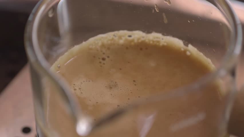 Drops of coffee extract into the measuring cup produce beautiful crema foam. | Shutterstock HD Video #1112013327