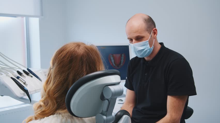 Blonde female patient in dentist chair listening to orthodontist instructions having medical treatment on teeth in professional clinic. Dental care. Oral hygiene. | Shutterstock HD Video #1112014935