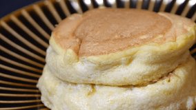 A video of pouring honey on soufflé pancakes. Close-up.