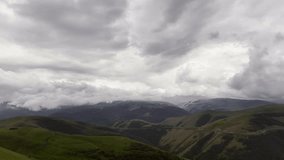 Clouds over the mountains as seen from a drone. Low clouds move along the mountain slopes, slowly enveloping the green summer landscape