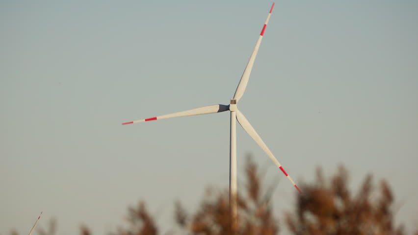 A wind turbine gracefully spinning against a stunning backdrop of a clear, vivid blue sky | Shutterstock HD Video #1112016643