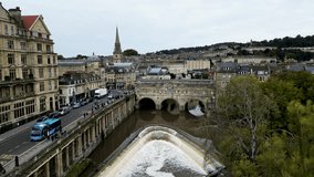 Top cinematic aerial view to the Georgian City of Bath and Bath Cathedral, Somerset, England. Pulteney Bridge and Weir on the river Avon, Bath, Somerset, England.